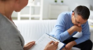 Female psychologist consulting pensive man during psychological therapy session